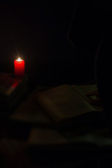 candle and a book of the Bible on wooden background at night