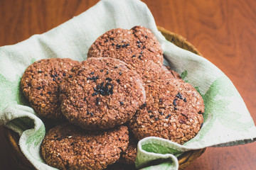 Homemade chocolate oatmeal cookies with white and black sesame seeds on a brown wooden table