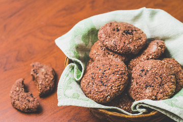 Homemade chocolate oatmeal cookies with white and black sesame seeds on a brown wooden table