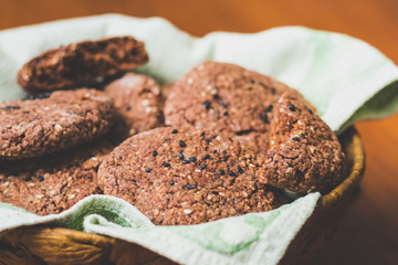Homemade chocolate oatmeal cookies with white and black sesame seeds on a brown wooden table
