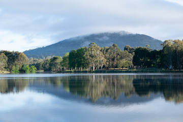 Fototapeta premium Reflection of hill and trees in Tuggeranong Lake