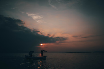 A fisherman tries to catch fish in sunset