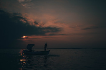 Fototapeta premium A fisherman tries to catch fish in sunset