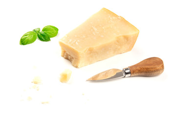 A piece of aged Parmesan cheese with crumbs on a white background with fresh basil leaves, a cheese knife, and a place for text