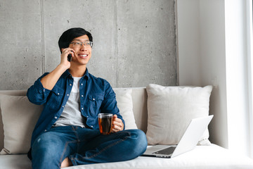 Smiling young asian man sitting on a couch