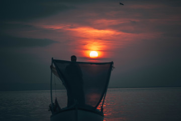 Sun goes down while fisherman throws his fishnet to collect fishes