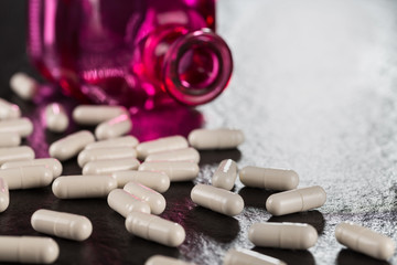 Close-up pile of white color medical pills on background vintage medical bottle made of red glass