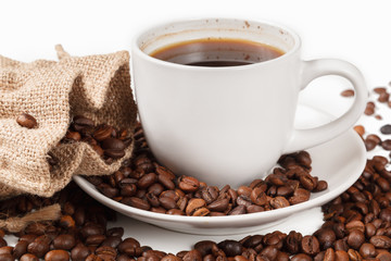 A Cup of strong coffee and a textile bag in roasted coffee beans, on a white background, isolated