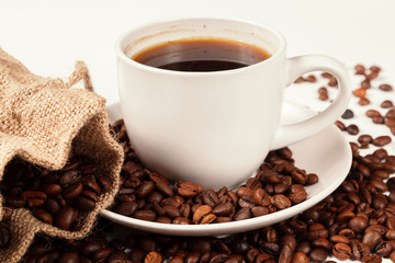 A Cup of strong coffee and a textile bag in roasted coffee beans, on a white background, isolated