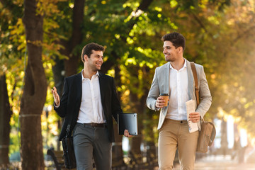 Two happy businessmen walking outdoors