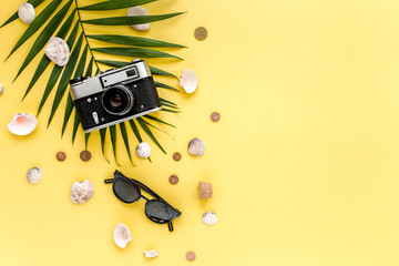 Fototapeta na wymiar Traveler accessories, tropical palm leaf branches on yellow background with empty space for text. Travel vacation concept. Summer background. Road frame set. Flat lay, top view.