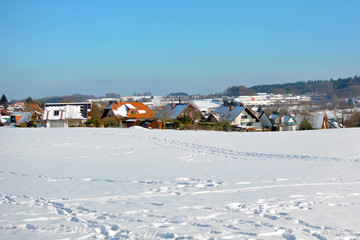 View of small rural town in Odenwald in Germany with clearing covered in snow during winter