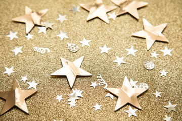 Fototapeta na wymiar Gold star sparkle party confetti on a gold glitter background