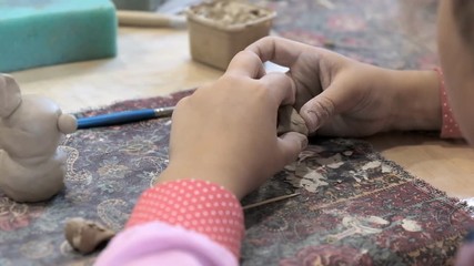 The child learns to mold different kinds of clay products in a ceramic workshop. - Powered by Adobe