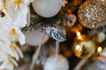 Gold decorations Christmas toys on the Christmas tree. Garland with bright yellow lights in artificial snow.