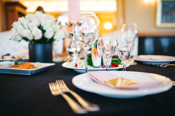 Dinner table serving. Violet and beige tones, pastel colors. Beautiful decoration of wedding banquet in restaurant with glasses, plates, forks and knives, white tablecloth.