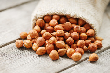 Chiselled hazelnuts in a bag of burlap on a gray wooden table. Organic Fresh Harvested