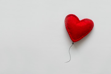 Valentines day card. Red felt heart shape balloon on thread. Minimalist concept