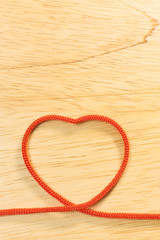 Red rope heart on wood plate valentine content.
