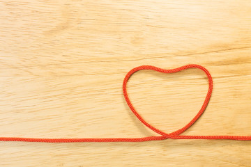 Red rope heart on wood plate valentine content.