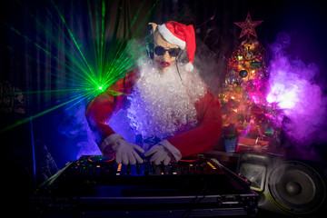 Dj Santa Claus at Christmas with glasses and snow mix on New Year's Eve event in the rays of light.
