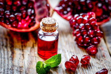 sliced pomegranate and extract in glass on wooden background