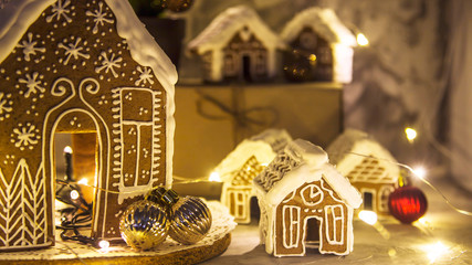 Fototapeta na wymiar Christmas still life with ginger houses and garland lights on gray background. Homemade Christmas Dessert Concept