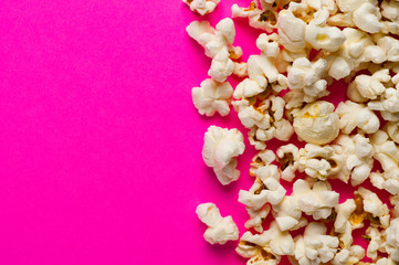 Scattered cooked popcorn on pink background with copy space. Сoncept of leisure