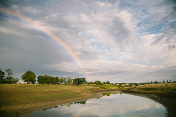 Summer field landscape after rain with rainbow. Eastern Europe, Ukraine