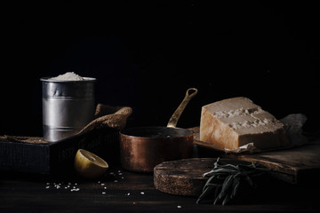 Female hands cooking risotto. Copper pan, rice, parmesan ingredients. Dark background