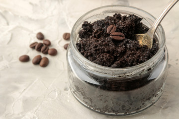 homemade coffee face and body scrub in a glass jar with a spoon on a light background. care cosmetics.