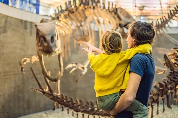 Fotobehang Dad and boy watching dinosaur skeleton in museum © galitskaya