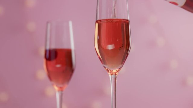 closeup slow motion serving pink rose sparkling wine and cherry falling in it then