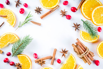 Winter autumn drink and food ingredients. Cranberries, sliced oranges, cinnamon, rosemary, anise for cooking cocktails, with christmas tree branches. Flatlay on white background. Top view copy space