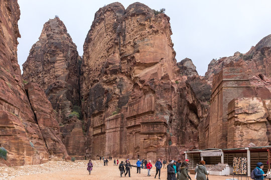 Numerous tourists go on the road leading between the red rocks in Petra - the capital of the Nabatean kingdom in Wadi Musa city in Jordan
