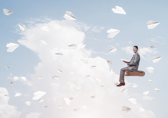 Businessman or student reading book and paper planes flying arou