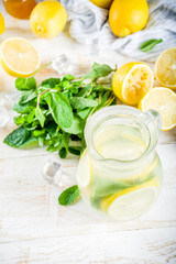 Homemade sour cocktail lemonade, with fresh lemons, mint and honey, white wooden background copy space