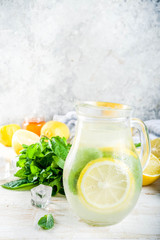 Homemade sour cocktail lemonade, with fresh lemons, mint and honey, white wooden background copy space