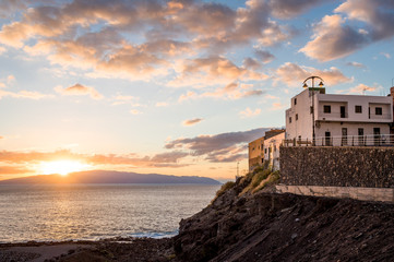 House on the rocks of Tenerife and sunset behind the La Gomera silhouette. Puerto Santiago, Canary islands, Spain.