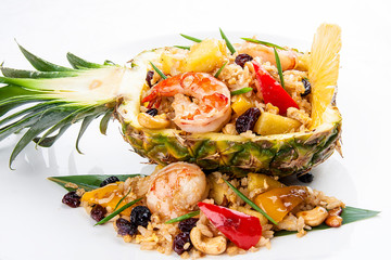 Cut pineapple stuffed with rice and Royal shrimps. On white background