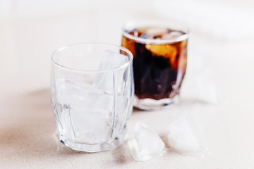 Full glass of cola, empty glass of cola - pieces of ice on the table - bar restaurant