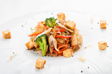 Wok vegetables with rice noodles and tofu cheese. Vegetarian dish. On white background