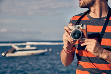 Obraz premium Man using vintage film camera on a ocean / sea vacation.