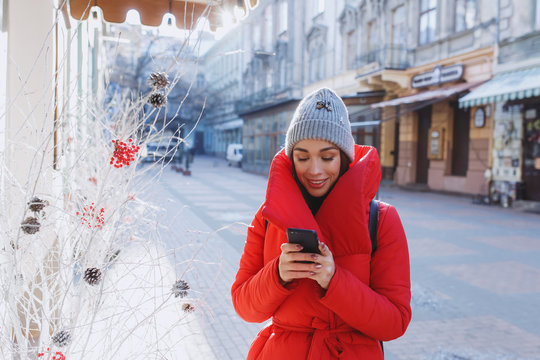 Happy wonam in red winter coat smile and text sms or message to friend.  Christmas, new year and winter holiday concept - Image