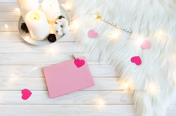 St. Valentine's Day concept. Pink letter on white wooden background with hearts, candles and garland. Copy space