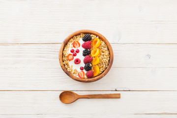 granola with berries on white wooden background