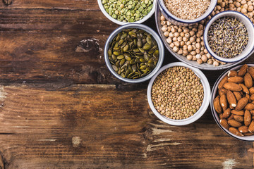 Composition of different types of legumes in bowls on wooden background