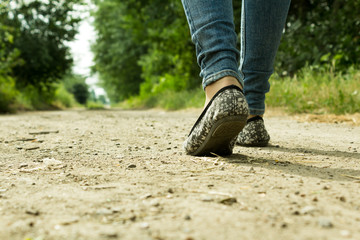 The girl goes on a dirt road through the trees