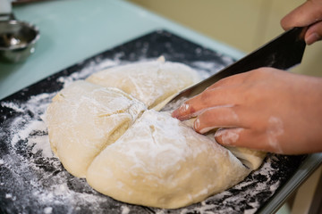 Cutting raw dough in flour with a knife (close-up of hands cutting dough)