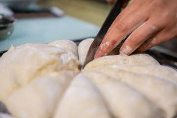 Cutting raw dough in flour with a knife (close-up of hands cutting dough)